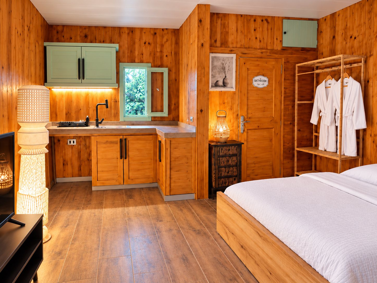 Le Chalet studio — wood-panelled room with kitchenette, bathroom door, bathrobes on a rack and bed